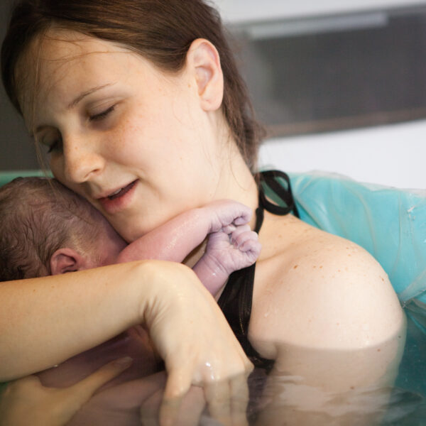 Mother Holding Newborn Baby in Birthing Pool After Home Birth