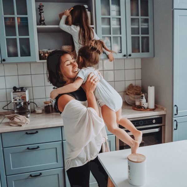 Mother practising calm parenting with toddlers causing chaos in kitchen